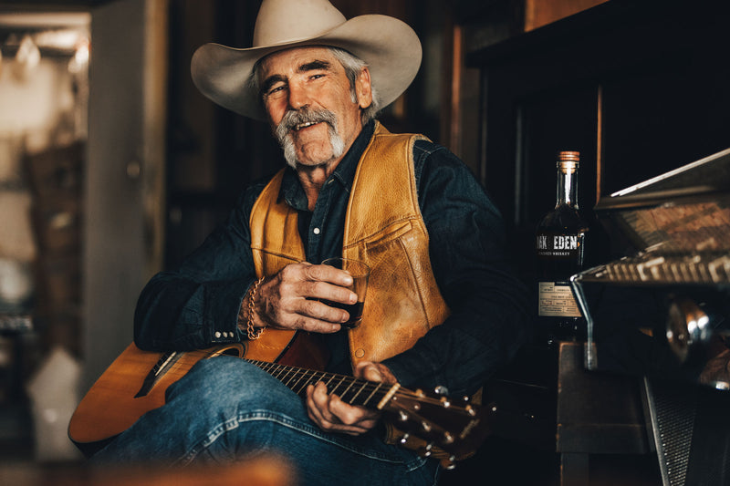 Forrie J Smith, actor on Paramount's Yellowstone TV show sitting with a glass of Oak & Eden Whiskey