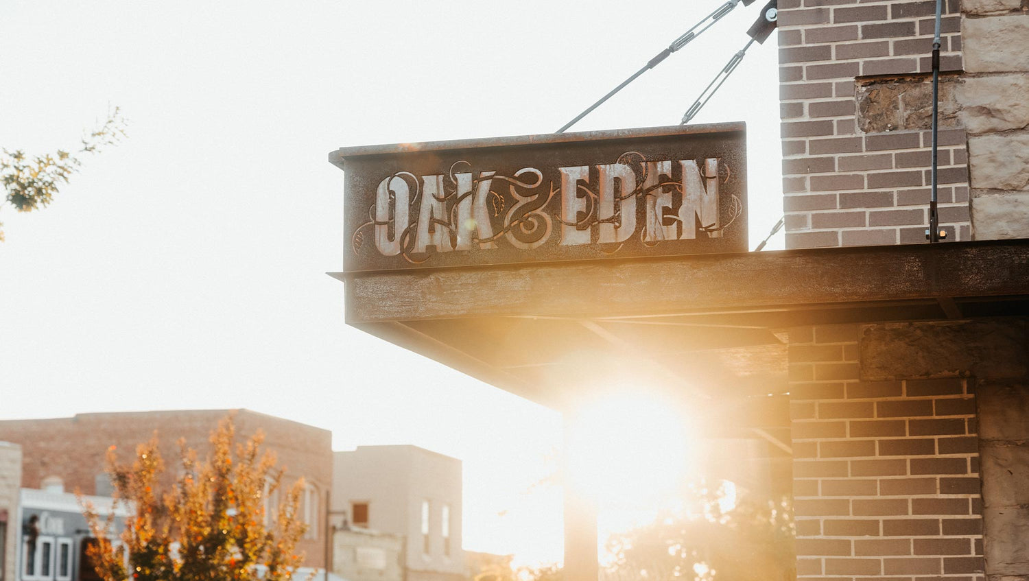 Oak & Eden flagship sign in Downtown Bridgeport, Texas. The sun is shining on a brick building as it sets.
